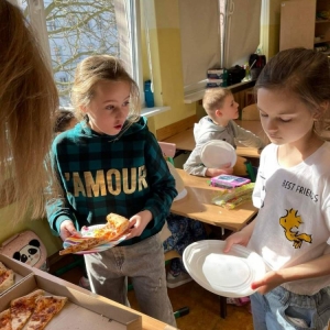 Uczniowie jedzą wspólnie pizzę