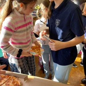 Uczniowie jedzą wspólnie pizzę